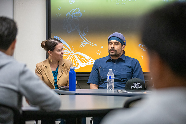 A woman and a man address the group of students