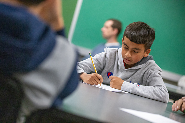 A teen boy writes down notes