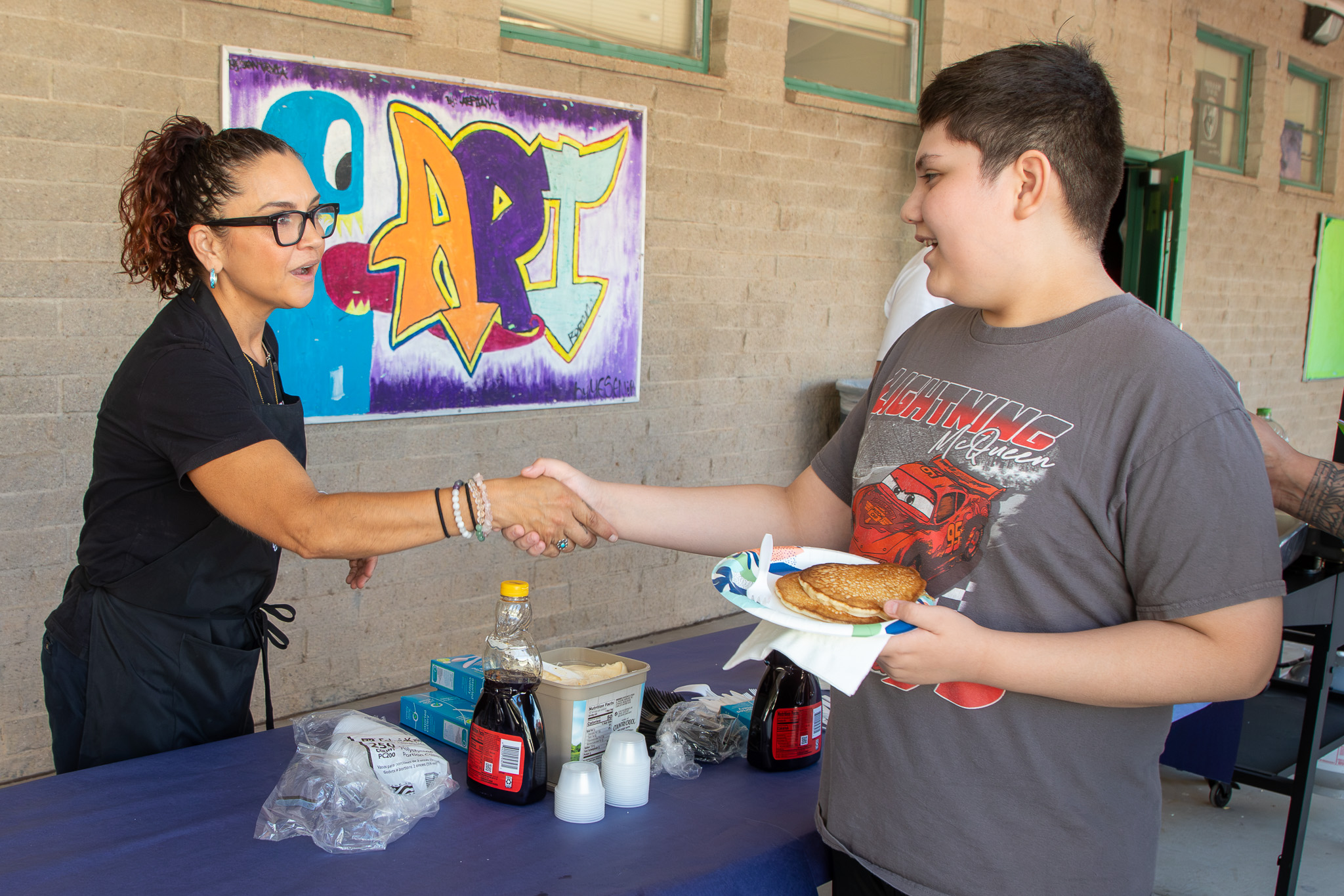 two women shaking hands over table